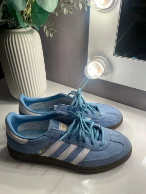 Adidas Spezial blå sneakers 38 - Säljer ett par Adidas Spezial sneakers i ljusblå mocka med vita detaljer och klassiska tre ränder på sidan. Skorna har snörning, Ortholite-innersula och mörkbrun yttersula.💗