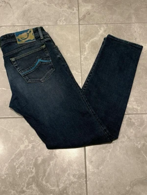 Jacob Cohën jeans - Snygga blå jeans från Jacob Cohën med unika gröna sömmar och detaljer. Har ett broderat J på fickan. Jeansen en skön passform. Perfekta för dig som gillar stiliga jeans. Storleken är i W34