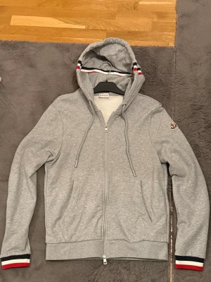 Moncler zip tröja  - En riktigt schysst Moncler zip i färgen grå och i nytt skick. Mycket snygg tröja med fina detaljer för dig som gillar att sticka ut! Priset kan diskuteras och hör gärna av dig vid frågor! OBS storlek är L men kan sitta bra på dig som bär M 