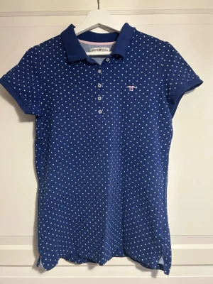 Prickig piké  - En blå, vitprickig piké med rosa detaljer från Hampton Republic! Alla knappar är intakta och den är i väldigt fint skick: sparsamt använd. Tröjslutet är breddat något, se sista bilden.