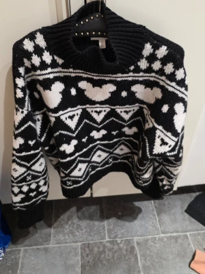 Svartvit stickad tröja från H&M - Säljer en svartvit stickad tröja från H&M i storlek L. Tröjan har ett coolt mönster med hjärtan och grafiska former, samt en hög ribbad krage. Materialet är 50% polyester, 45% akryl och 5% ull. Perfekt för kalla dagar och riktigt mysig!