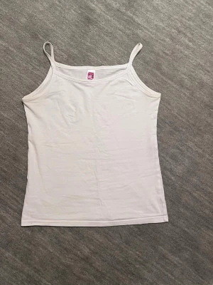 Basic vitt linne - Klassiskt vitt linne i bomull. Storleken är 146/152 men skulle säga att den motsvarar en XS. Linnet är i ett bra skick.