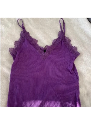 Lila linne med spets  - Säljer en lila  linnetopp från Amisu med tunna justerbara axelband och vacker spetskant längs urringningen samt nertill storlek M