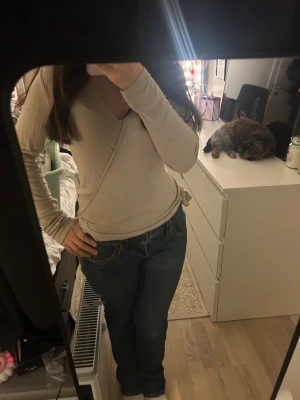 Beige omlottopp från 157, storlek S - Snygg beige omlottopp från 157 i mjuk bomull. Toppen har lång ärm, v-ringning och knyt i sidan för en chill och feminin look. Perfekt att matcha med jeans eller kjol. Enkel och stilren design som funkar året runt.