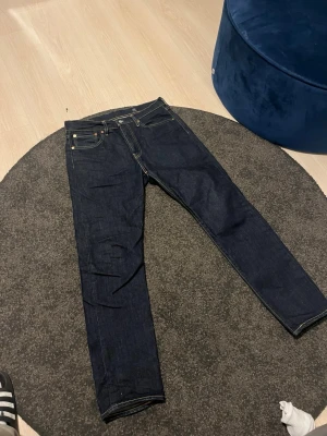 Levi's 511 mörkblå jeans W33 L32 - Säljer ett par Levi's 511 Premium jeans i mörkblå denim. Klassisk femficksmodell med raka ben och snygga kontrastsömmar. Jeansen är tillverkade i bomull och har en stilren look med läderpatch bak och Levis röda etikett på bakfickan. Använda 2-3 gånger! Pris kan diskuteras!