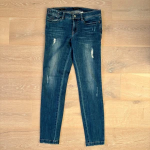 Miss Sixty skinny jeans med dragkedja - Säljer ett par jeans från MISS SIXTY, tillverkade i Italien, i mycket fint skick. Kvaliteten är exceptionellt hög, med ett stadigt men följsamt denimtyg (92,6 % bomull). Modellen (JJ3670DX9018L6J970) är lågmidi med en riktigt smickrande passform och tydlig MISS SIXTY-silhuett. Detaljerna är välgjorda – inklusive dragkedjor vid bensluten, subtila slitningar framtill och karakteristiska bakfickor. Storlek: 27 Midja: 76 cm Byxlängd: 93 cm Passform: Low waist Material: 92,6 % bomull Ett par mångsidi