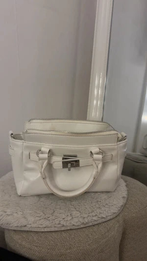 Vit handväska från Stradivarius  - Snygg vit väska köpt när jag var i Grekland i somras på Stradivarius ! Jättesnygg och praktisk med ett innerfack inuti.❣️säljer då jag inte använder längre