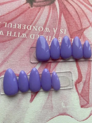 Lila lösnaglar i mandelform - Säljer ett set med lila lösnaglar i mandelform, perfekta för att få snygga och trendiga naglar på nolltid. Naglarna har en blank finish och kommer i olika storlekar för att passa alla fingrar. Materialet är plast gele och färgen är en cool lila nyans.