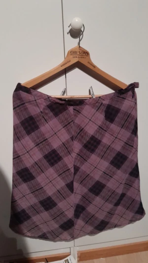 Rutig kjol - En lila rutig kjol. Har en dragkedja på sidan.