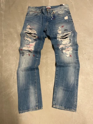 Tommy Hilfiger distressed jeans  - Säljer dessa Tommy hillfiger distressed denim, dom kommer med prislapp och har cool design med distressing. Slim fit, storlek 32/32, riktigt bra statement piece. Original tags är inkluderade Öppen för rimliga prisförslag
