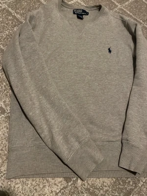Grå Ralph Lauren tröja - Fet grå tröja från Ralph Lauren, tröjan är storlek S och i nytt skick.Jag säljer tröjan för att den är lite för stor för mig. Säljer för bra pris.
