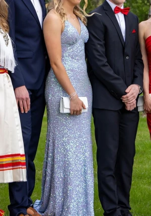 Glittrig ljuslila långklänning - Säljer min ljuslila balklänning från dressroom linne stl 34 (nypris 4990:-). Klänningen är använd två gånger och är i bra och fint skick. Den har tappat lite paljetter och det är ett lite område (ca 3cm i diameter) längst ner på klänningen som saknar paljetter. Finns även en fläck på innertyget nere vid marken, men inget som syns. Kan skicka bilder. Är uppsydd ca 3cm för att passa mig 167 cm med 8cm höga klackar, går nog att släppa ner igen om man vill. 