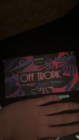 NYX Off Tropic ögonskuggspalett - NYX Off Tropic ögonskuggspalett med 10 färgstarka nyanser i rektangulära pans. Paletten har tropisk design med lila, rosa och blått på förpackningen. Skuggorna är matta och skimrande i orange, rosa, guld, grönt, blått, rött och lila. Perfekt för kreativa looks.