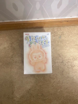 Beige pälsväst från Pop Mart - Säljer en beige pälsväst inspirerad av Pop Mart Biginto Energy, med fluffig look och rundad form. Västen har söta detaljer som kaninöron och är tillverkad i mjuk pälsimitation. Perfekt för dig som gillar gulliga och unika plagg.