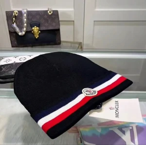 Moncler mössa med röd, vit och blå rand - Snygg svart mössa Moncler med breda ränder i rött, vitt och marinblått längs kanten. Mössan har Moncler-logga framtill och är stickad i mjukt material som sitter skönt på huvudet. Perfekt för dig som vill ha en clean och sportig look.