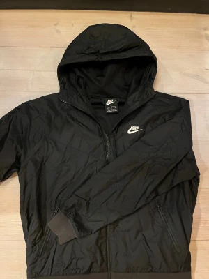 Svart Nike vindjacka strl M - Svart vindjacka med huva från Nike. Storlek M