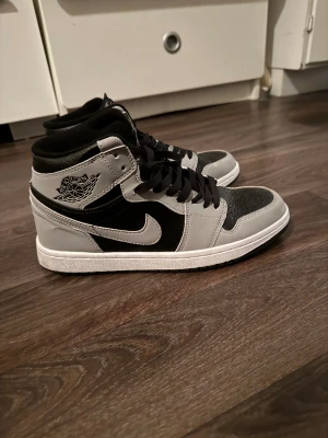 Nike Air Jordan 1 svart/grå sneakers - Säljer ett par Nike Air Jordan 1 sneakers i svart och grått. Sitter jätte skönt och bra har använt 2 två gånger bara. jag tyckte att dom var lite för små det är därför jag säljer dessa Jordan 1. Men som jag sa så är dem sköna att ha och är i jättebra kvalitet. Jag  köpta dessa skor från JD för 1500kr
