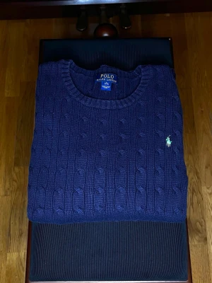 Ralph Lauren Mörkblå stickad tröja  - Ikonisk Cable Knit från Polo Ralph Lauren i navy, storlek XL. Tidlös, i nyskick utan prislapp. Perfekt för dig som vill addera ett elegant, premiumbasplagg till garderoben.  Snabb leverans.🚚 