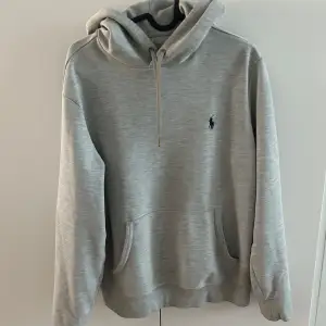 Säljer en stilren grå hoodie från Ralph Lauren med en klassisk känguruficka och justerbar huva. Den har en liten broderad logga på bröstet. Perfekt för en avslappnad look. Storleken är S