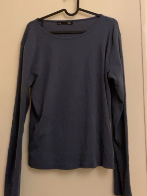 Marinblå långärmad topp i bomull - Säljer en enkel och stilren marinblå långärmad topp från Lager 157. Toppen har rund halsringning och är gjord i mjuk bomull, perfekt för att bygga lager eller bära som den är. Passar dig som gillar basic och clean look.