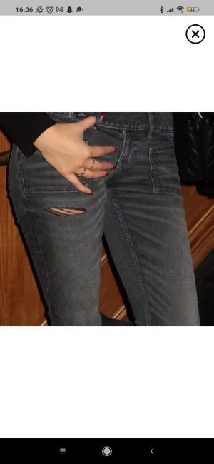 Bootcut svarta jeans med slitningar - Snygga bootcut jeans i mörkgrått med slitna detaljer på låren och knäna. Modellen har låg midja, två knappar i linningen och klassiska fickor fram. Jeansen är tillverkade i denim och har en cool, lite vintage vibe. Säljer vidare då de inte passar mig. I storlek Xs från Gina Tricot 14+💞
