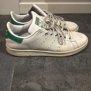 Adidas Stan Smith  - Klassiska Adidas Stan Smith sneakers i vitt med gröna detaljer. Ena skins läder har gått upp lite så det förklarar priset. Storlek 38 och 2/3 men passar 38 och 39! Skriv för mer bilder!💖📸