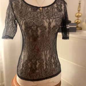 Svart spets tröja - En både basic och fest tröja i svart spets med dragkedja på ryggen. Från ” 3 Suisses Collection ” i storleken Small/Medium.