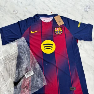 FC Barcelona kortärmad matchtröja Nike - Säljer en  FC Barcelona fotbollströja från Nike med klassiska blå och röda vertikala ränder, klubbmärke på bröstet och gul Nike-logga. Tröjan har rund hals, korta ärmar och är tillverkad i lätt, ventilerande polyester. Spotify-logga i gult på framsidan.