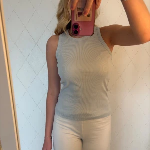 Ljusblå ribbad linnetopp från Diesel - Säljer en ljusblå ribbad linnetopp från Diesel med broderad logga i svart och rött på ryggen. Toppen är ärmlös med rund halsringning och har en tight passform. Perfekt till sommaren och enkel att matcha med olika outfits.