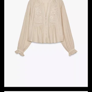 Beige broderad blus med volangärm - Supersöt beige blus med broderade detaljer framtill och små knappar längs hela framsidan. Långärmad modell med volang vid ärmslut och lätt rynkad passform. Perfekt för dig som gillar romantisk och bohemisk stil.
