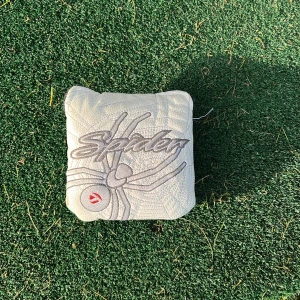 Vit TaylorMade Spider headcover - Vit fyrkantig headcover från TaylorMade med broderad spindel och texten 'Spider' på framsidan. Tillverkad i skinn med mjuk insida och kardborrestängning. Passar perfekt till golfutrustningen och ger en sportig look. Den är lite använd men funkar för ett billigt och bra pris