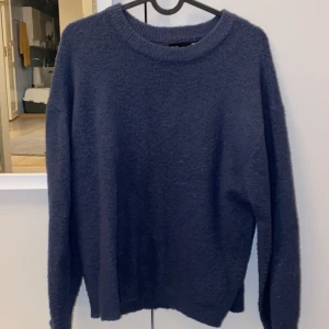 Mörkblå stickad tröja från 157 XS - Mysig mörkblå stickad tröja från 157 i storlek XS. Tröjan har rund halsringning, ribbade muddar och långärmad passform. Materialet är mjukt och fluffigt, perfekt för kyliga dagar. Enkel och stilren design som är lätt att matcha med dina favoritjeans.