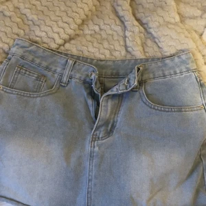 Ljusblå jeanskjol med fickor - Snygg ljusblå jeanskjol i klassisk modell med fem fickor, bälteshällor och dragkedja framtill. Kjolen har en rak passform och är perfekt för en avslappnad stil. Materialet är denim och kjolen slutar ovanför knäna.