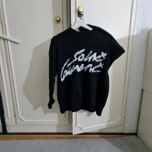 Svart stickad Saint Laurent tröja - Pris kan deskuteras kan dessutom sicka mer bilder privat.Svart stickad tröja från Saint Laurent med vit, stor logga framtill i coolt mönster. Tröjan har lång ärm och klassisk rund halsringning. Perfekt för dig som vill ha en statement piece med lyxig känsla. Köpte som M men passar som S