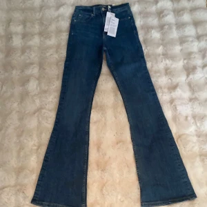 High bootcut jeans från Perfect Jeans - Snygga blå jeans med high bootcut-modell från Perfect Jeans. Hög midja och klassisk femficksdesign. Jeansen har en mörkblå tvätt och är tillverkade i mjukt denimtyg som sitter skönt och ger en trendig siluett. Köptes för 500 kr 