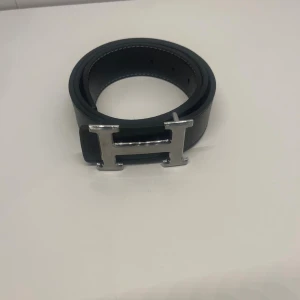 Bälte  - Ett svart bälte med silvrig H, den är helt ny och är i 105 cm. Pris kan diskuteras och skriv om du har några frågor. 