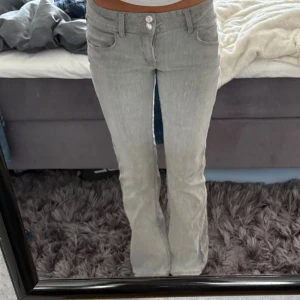 Ljusgrå bootcut jeans - Säljer ett par ljusgrå jeans med bootcut-modell och två knappar i midjan. Snygg passform som sitter tajt upptill och släpper ut vid benen. Perfekta för dig som gillar en klassisk men trendig look. Skriv gärna för frågor ❤️
