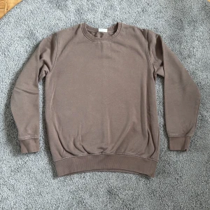 Brun sweatshirt från Kappahl - En basic brun sweatshirt från Kappahl i storlek 158/164. Tröjan har rund halsringning, ribbade muddar vid ärmslut och nederkant samt är tillverkad i mjuk bomullsmix. Perfekt för en chill och avslappnad stil.