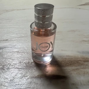 Dior Joy parfymflaska - Trendig parfym från Dior med modern design och rosa innehåll. Perfekt för dig som vill sticka ut med en ikonisk flaska på hyllan. Volym och ingredienser syns ej på bilderna.