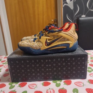 Nike sneakers i gult och blått, strl 41 - Unika Nike sneakers med coolt mönster i gult och beige, blå sula med färgstänk och röda detaljer. Snyggt broderad Swoosh på sidan, snörning och platt sula. Insidan är röd och skorna har nummer 07 bak. Perfekt för dig som vill sticka ut.