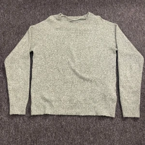 Grön stickad tröja från Vero Moda - Mysig grönmelerad stickad tröja från Vero Moda i storlek XS. Tröjan har rund hals, ribbade muddar vid ärmslut och nederkant samt långärmad passform. Perfekt för att hålla värmen under kyliga dagar.