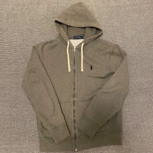 Raulph lauren zip hoodie - Säljer en mycket fint Raulph lauren hoodie som är grå fast kan uppfattas mer som mörkgrå. Hoodie är fint skick och storleken small. Pris kan diskuteras vid snabb affär. Denna hoodie är mycket eftertraktad.