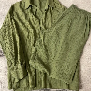 Olivgrön skjorta i krinklad bomull - Olivgrön skjorta med avslappnad passform och krinklad struktur. Skjortan har klassisk krage, knäppning framtill och långa ärmar med manschett. Tillverkad i mjuk bomull som känns lätt och luftig. 