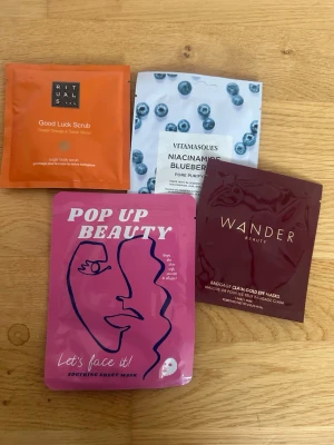 Ansiktsmasker och ögonmasker mix -  ansiktsmasker och ögonmasker och skrubb i färgglada förpackningar. Inkluderar en orange skrubb från Rituals, en blåbärsmask från Vitamasques, en rosa sheet mask från Pop Up Beauty och en vinröd ögonmask från Wander Beauty. Perfekt för en self-care kväll.
