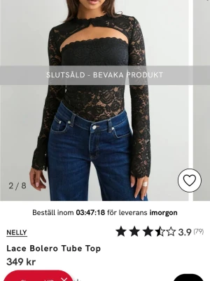SÖKER!!! storlek S/M - Supersnygg svart bolerotopp i spets från Nelly med tubtopp och långärmade detaljer. Toppen har ett unikt omlott-utseende över axlarna och är croppad med transparent spetsmaterial. Perfekt att styla med jeans eller kjol för en trendig look.