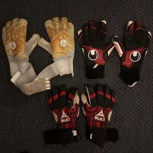 Målvaktshandskar Uhlsport - Bara uhlsport kvar  Säljer tre par målvaktshandskar: ett par guld- och vitfärgade TZZ med bred kardborre, ett par svart-röda Uhlsport med coola detaljer och ett par röd-svarta Select med vita inslag. Alla har greppvänlig insida och justerbar handledsrem. Perfekta för fotbollsmålvakter. 