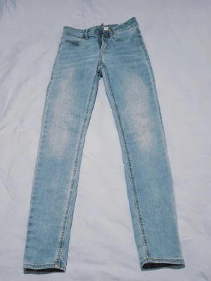Cubus Jane Skinny Jeans - Ljusblå Stretch, Hög Midja - Strl S/34 - Säljer ett par helt nya och oanvända (NWT-skick, inga lappar men aldrig använda) jeans från Cubus. Modellen heter Jane Skinny och är en klassisk skinny fit-modell med lite högre midja. Jeansen har en snygg, ljusblå tvätt och är tillverkade i ett stretchigt material för bästa komfort och passform. Märke: Cubus Modell: Jane Skinny Storlek: S/34 Mått: Midjan mäter cirka 35 cm rakt över Längd: 100 cm
