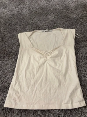 Vit v-ringad topp från lager 157 i storlek M - Säljer en beige topp från lager 157 i storlek M. Toppen har v-ringning med snygg rynkning framtill och är ärmlös. Materialet är mjuk bomull och modellen är enkel och clean, perfekt till jeans eller kjol.💕