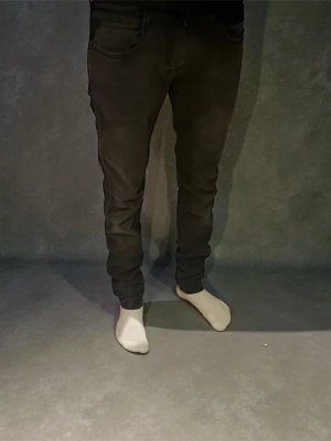 Svarta Replay anbass hyperflex jeans - Svarta hyperflex jeans från Replay med klassisk femficksdesign och smal passform. Jeansen har en snygg mörk tvätt och raka ben med lätt tapered siluett. Materialet är mjukt och stretchigt jeans, perfekt för dig som gillar stilrena och bekväma byxor. Byxorna är W30 L32.