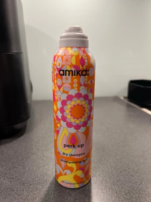 Amika Perk Up torrschampo 234 ml - Amika Perk Up torrschampo i en färgglad sprayflaska med retroinspirerat mönster. Innehåller 234 ml och är perfekt för att fräscha upp håret mellan tvättarna. Flaskan är orange, rosa och gul med blommiga detaljer och har en praktisk sprayfunktion.   Nypris ca 400kr.  Helt oanvänd.  Tyvärr har locket flygigt av och jag hittar den inte tyvärr